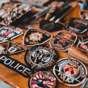Collection of diverse police and security badges displayed on a wooden table surface.